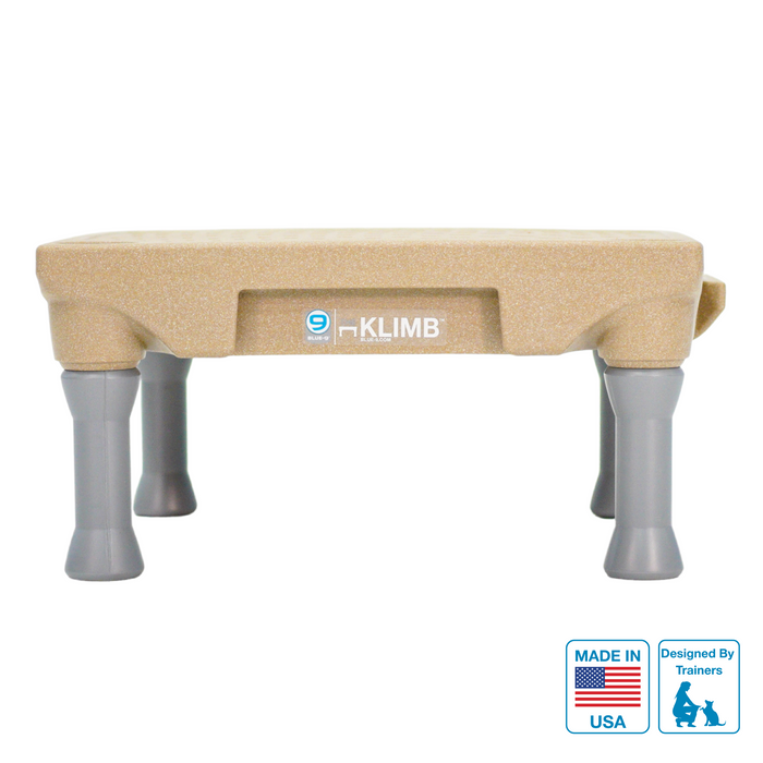 A tan KLIMB dog training platform with the KLIMB brand logo, marked as made in the USA, with removable legs.