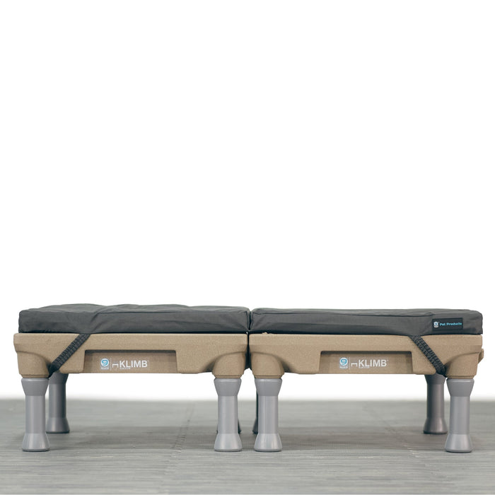A large, grey, durable dog bed with water-resistant properties, featuring built-in carrying handles and designed to fit on top of two Klimbs.